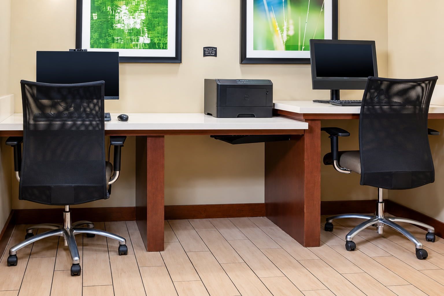 Une salle de conférence équipée de deux bureaux, chacun comprenant un ordinateur et une chaise.
