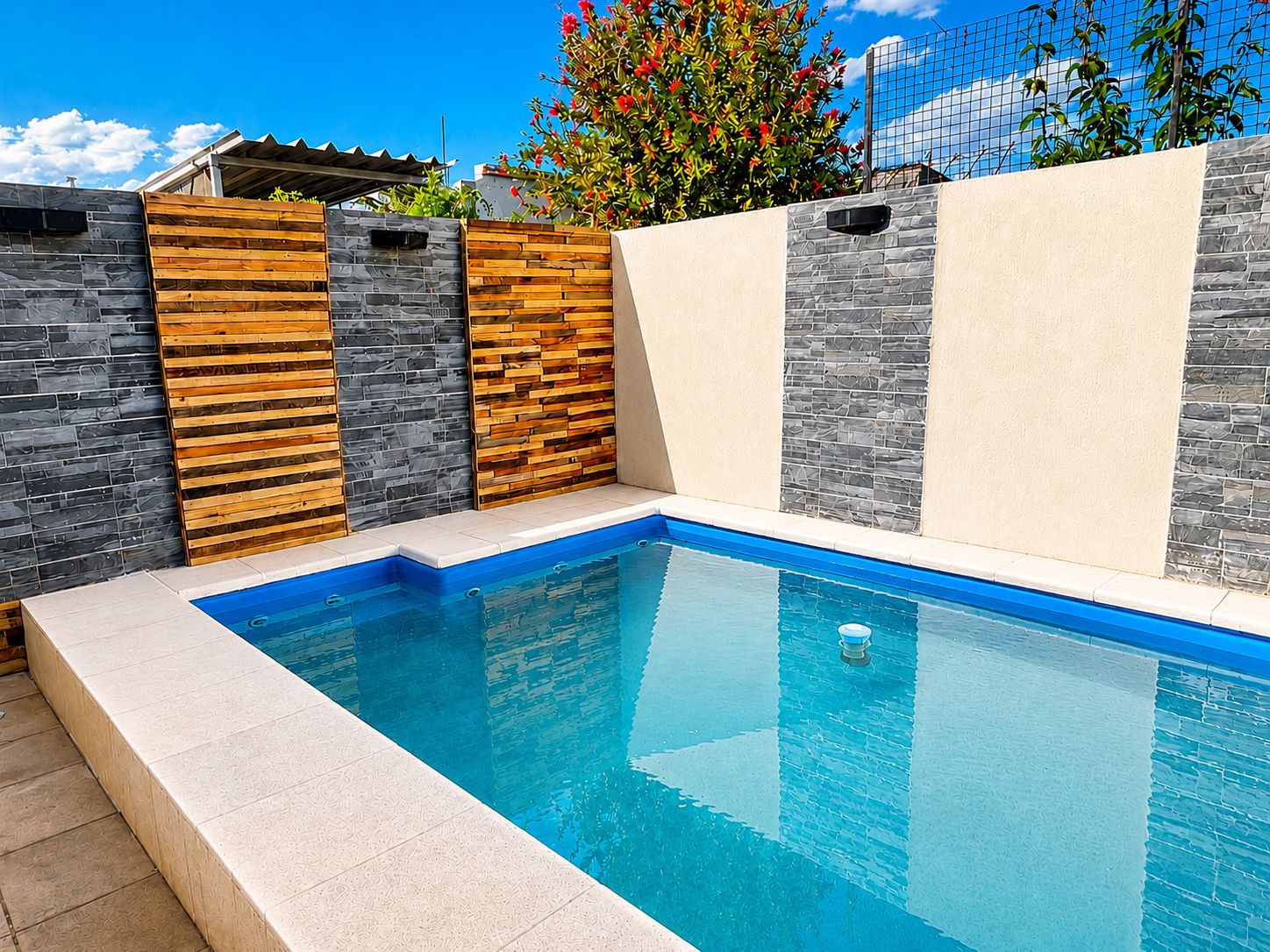 A rectangular swimming pool with a blue interior, surrounded by a tiled deck.
