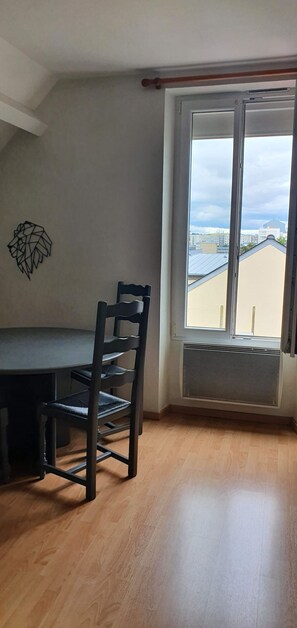 Ein Essbereich mit Tisch und Stühlen, einem Heizkörper und einem Fenster mit Blick auf Gebäude.