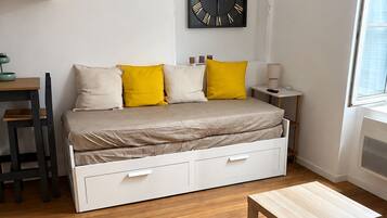 A bedroom with a bed, bedside table, lamp, and a wall clock.