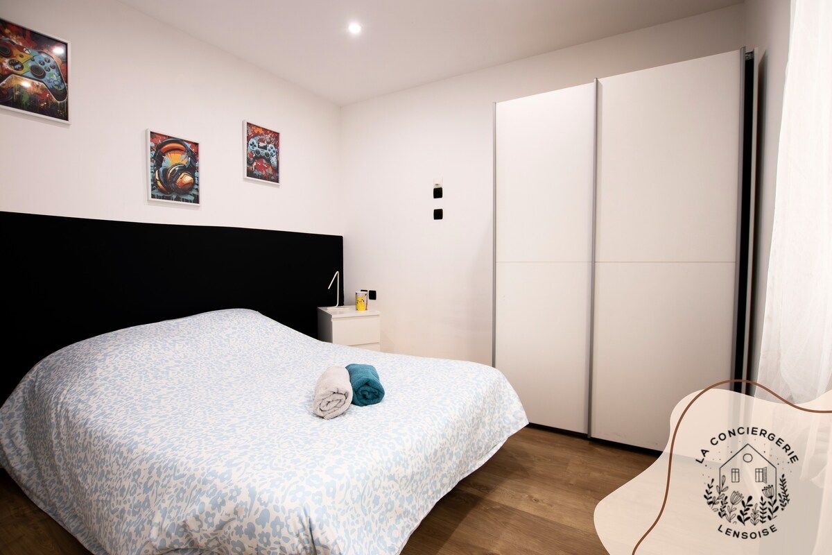 A bedroom with a bed, a nightstand, a wardrobe, and artwork on the wall.