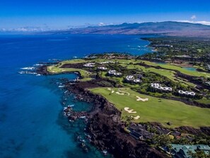 An aerial view of a coastal golf course with multiple holes, lush greenery, and a clear blue ocean. - Mauna Lani Point - 4 BR (2 condos), Sleeps 8 (Waimea)