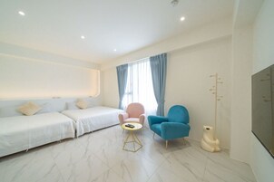 Una habitación de hotel moderna con un sofá, dos sillones, una mesita y un televisor.