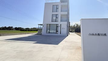 A modern building with a flat roof, large windows, and a balcony.