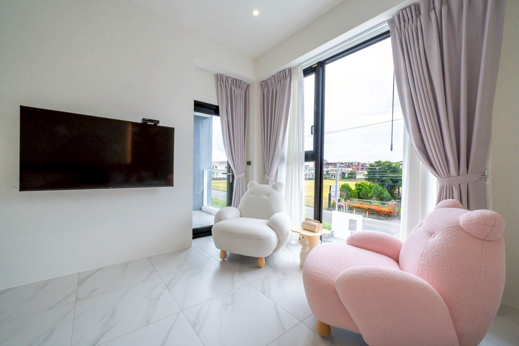 Una sala de estar moderna con un televisor de pantalla plana montado en la pared, un sillón cómodo y un sofá.
