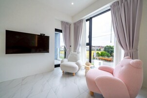 Una sala de estar moderna con un televisor de pantalla plana montado en la pared, un sillón cómodo y un sofá.