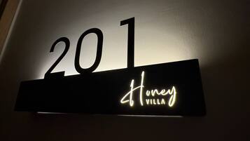 A sign with the number '201' and the name 'Honey Villa' illuminated in white.