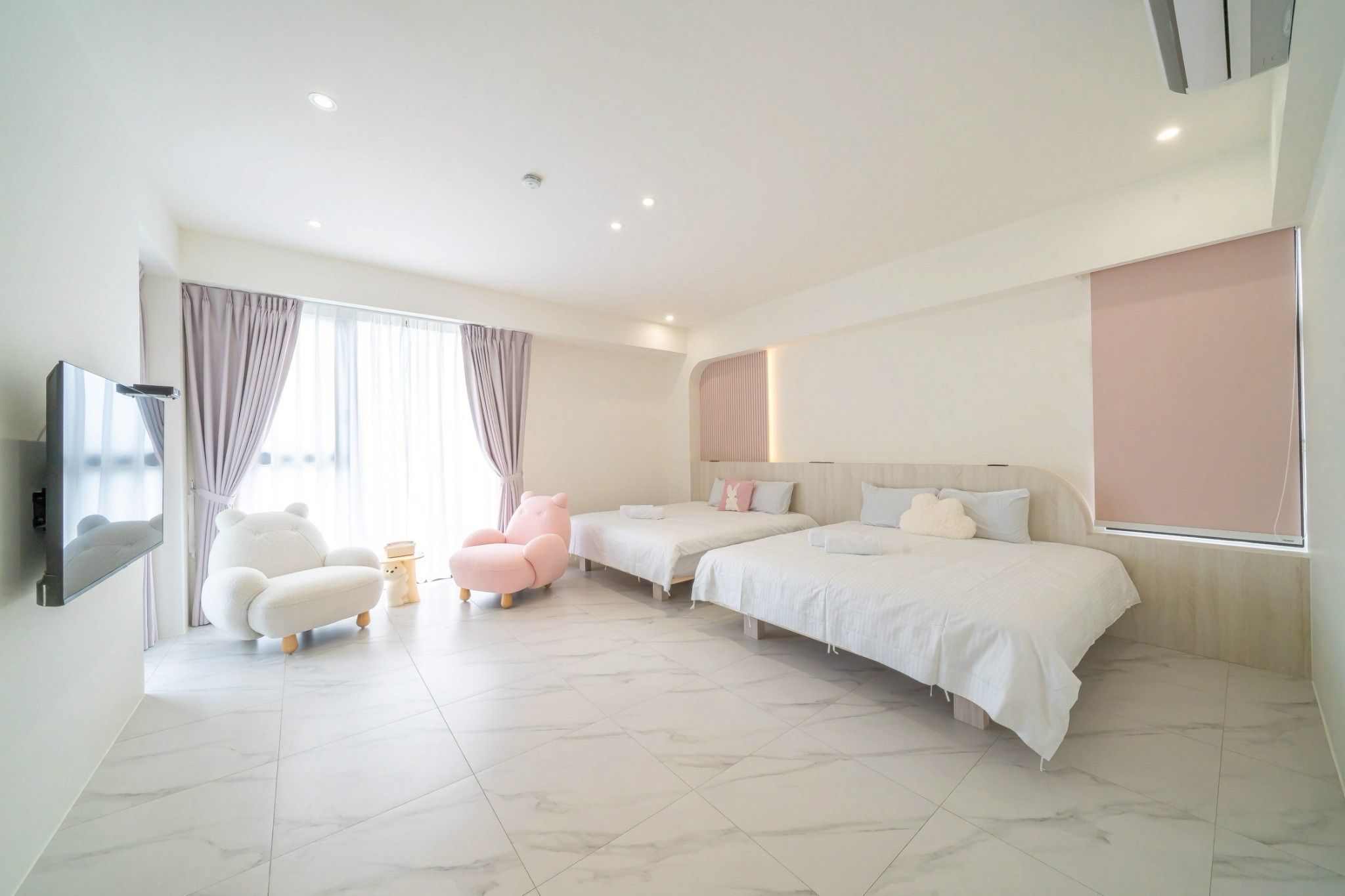 Una habitación de hotel moderna con una cama grande, un sofá, una silla y un televisor.