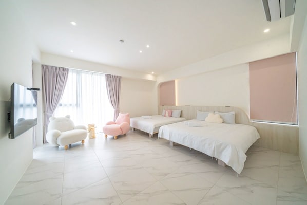 A modern hotel room with a large bed, a sofa, a chair, and a TV.