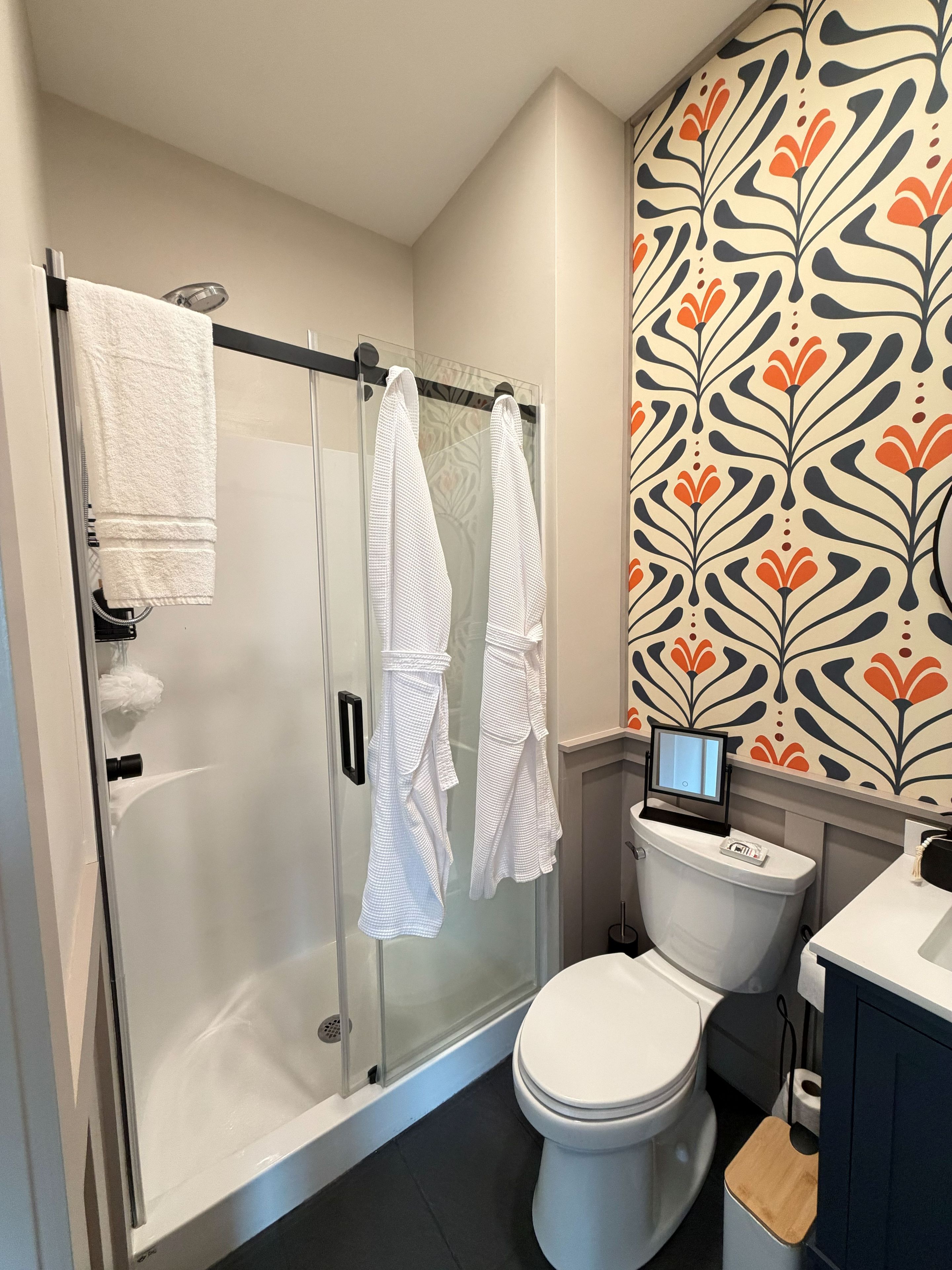 A bathroom with a glass shower enclosure, a toilet, and a sink.