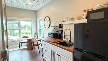 A kitchen with a modern design, featuring a black refrigerator, wooden countertops, and a geometric ceiling pattern.