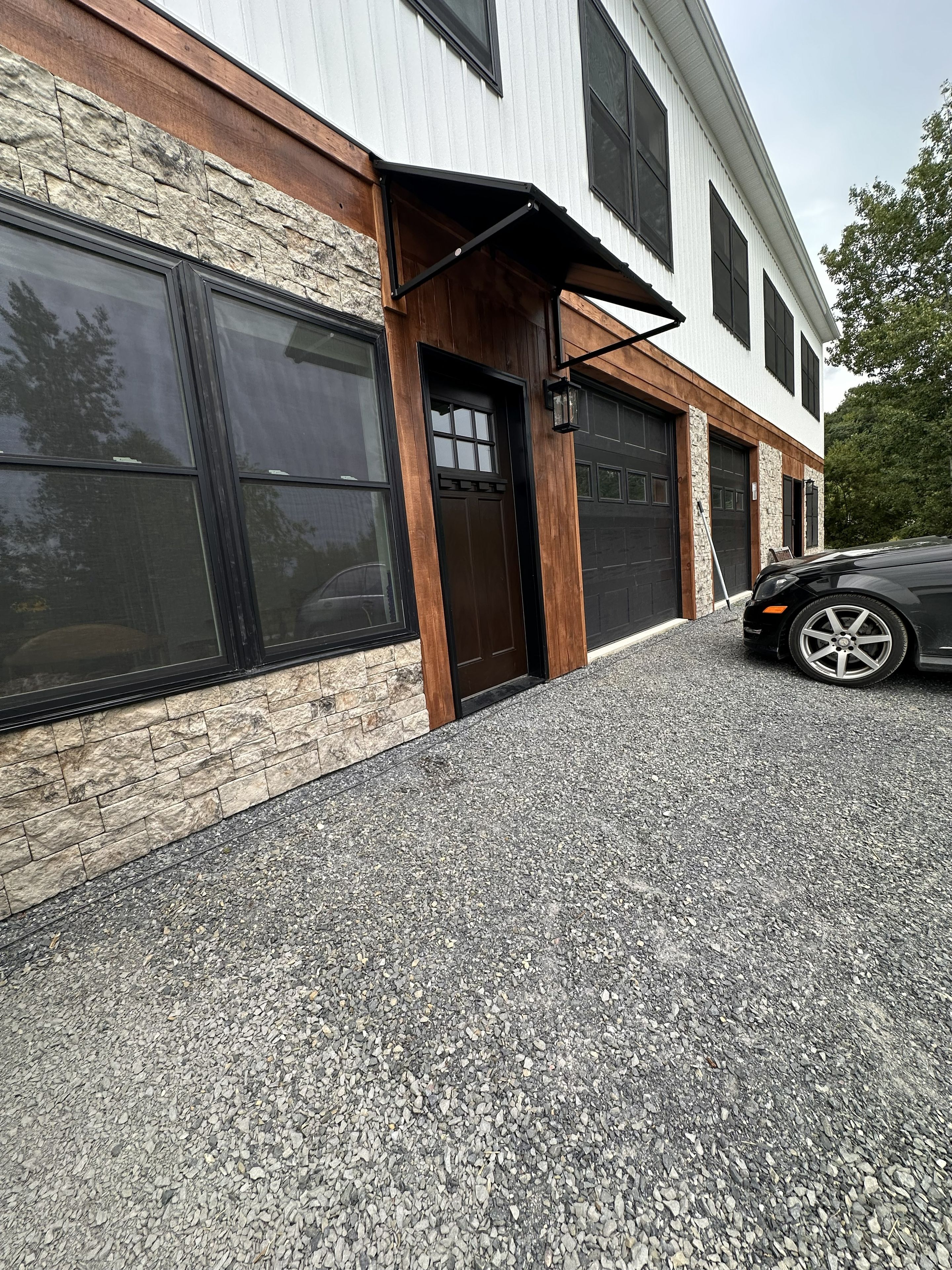 Un bâtiment moderne avec une façade en pierre, de grandes fenêtres et un garage.