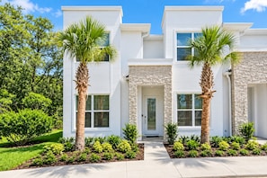 A modern two-story house with a stone facade, a central entrance, and two palm trees in the front yard. - The Clermont Palm Retreat (Clermont)