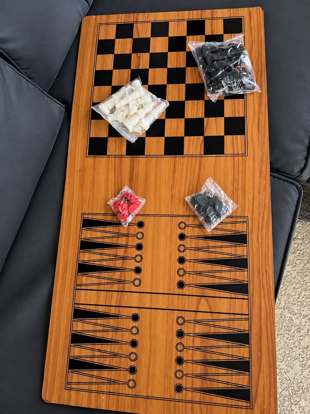 A wooden board game table with checkered and patterned designs, accompanied by bags of game pieces.