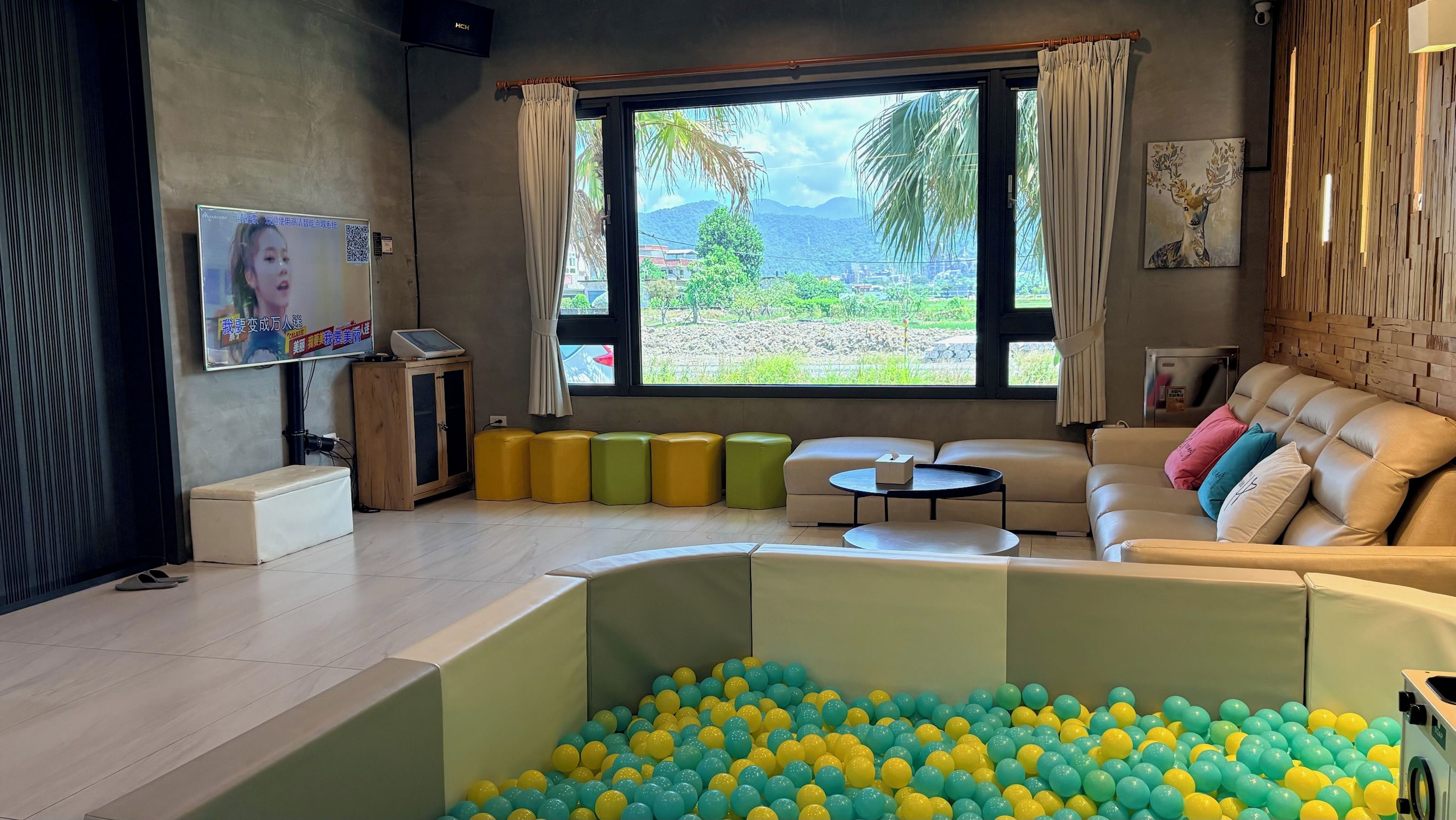 Una sala de estar moderna con un foso de pelotas, un sofá, un televisor y vistas al exterior.