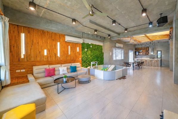 A spacious living area with a sofa set, a coffee table, and a seating area with stools.