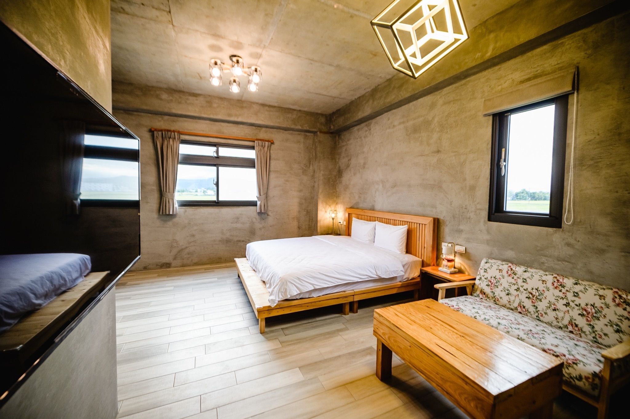 Una habitación con una cama, un sofá, una mesa de madera y una ventana.