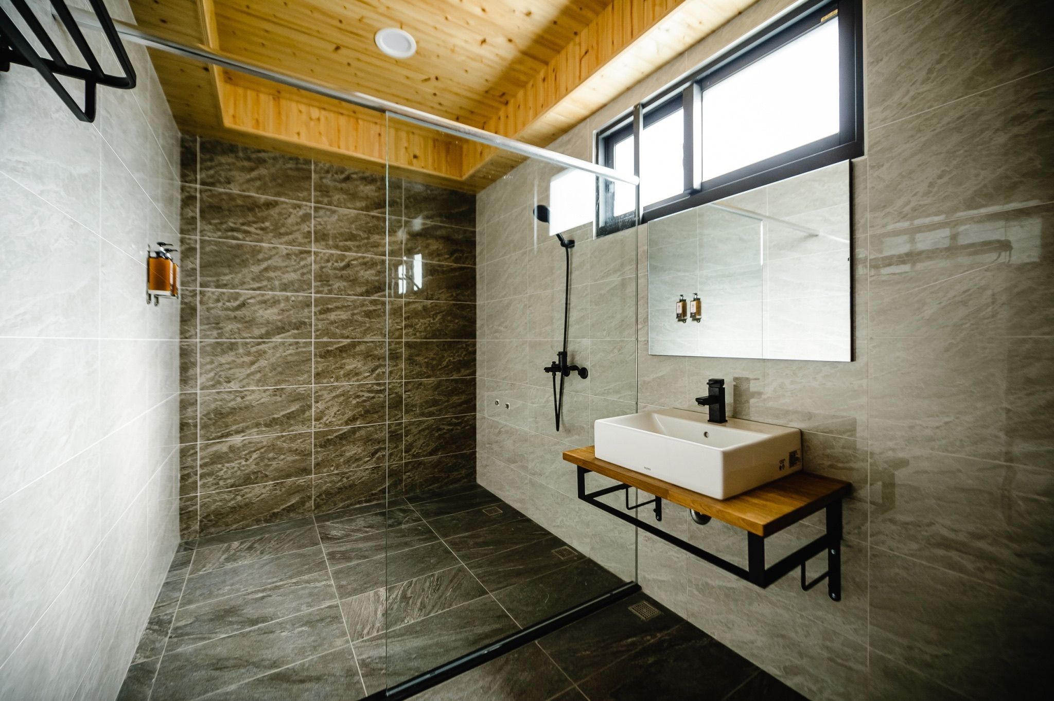 A modern bathroom with a glass-enclosed shower, a wooden vanity, and a large mirror.