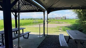 An outdoor pavilion with picnic tables and a view of a green field.