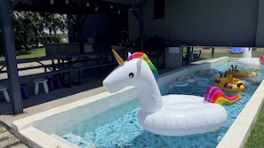 An outdoor swimming pool with inflatable toys, including a unicorn float and various animal-shaped floats. - H Villa YiLan (Dongshan)