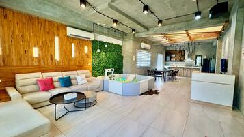 A modern living room with a sectional sofa, a coffee table, and a play area with balls.