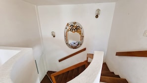 A staircase with a wooden handrail, a wall-mounted mirror, and a light fixture. - Spacious Ocean view 4 bedroom house with pool close to Bacocho beach (Puerto Escondido)