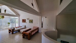 A spacious living area with a sofa, a dining table, and a bench. There is a door leading to another room and a window with a view. - Spacious Ocean view 4 bedroom house with pool close to Bacocho beach (Puerto Escondido)