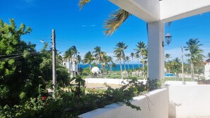 A coastal view with palm trees, a white building, and a clear blue sky. - Spacious Ocean view 4 bedroom house with pool close to Bacocho beach (Puerto Escondido)