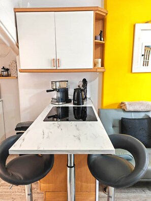 A compact kitchen with a white countertop, two black chairs, a coffee maker, and a kettle. - Clean, Cosy, Homely - city access right outside (Edinburgh)