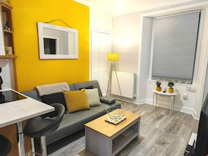 A modern living room with a sofa, coffee table, and a small side table with plants. - Clean, Cosy, Homely - city access right outside (Edinburgh)