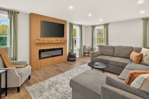 A modern living room with a fireplace, a flat-screen TV mounted above it, and a comfortable seating area with a sofa and armchairs. - Newly Remodeled | Near Wineries | Sleeps 10 (Dundee)