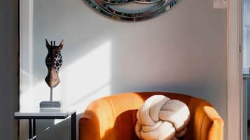 Un saló modern amb un relaxant gandissa taronja, una obra d'art rodona penjada a la paret i una petita escultura sobre una taula auxiliar.
