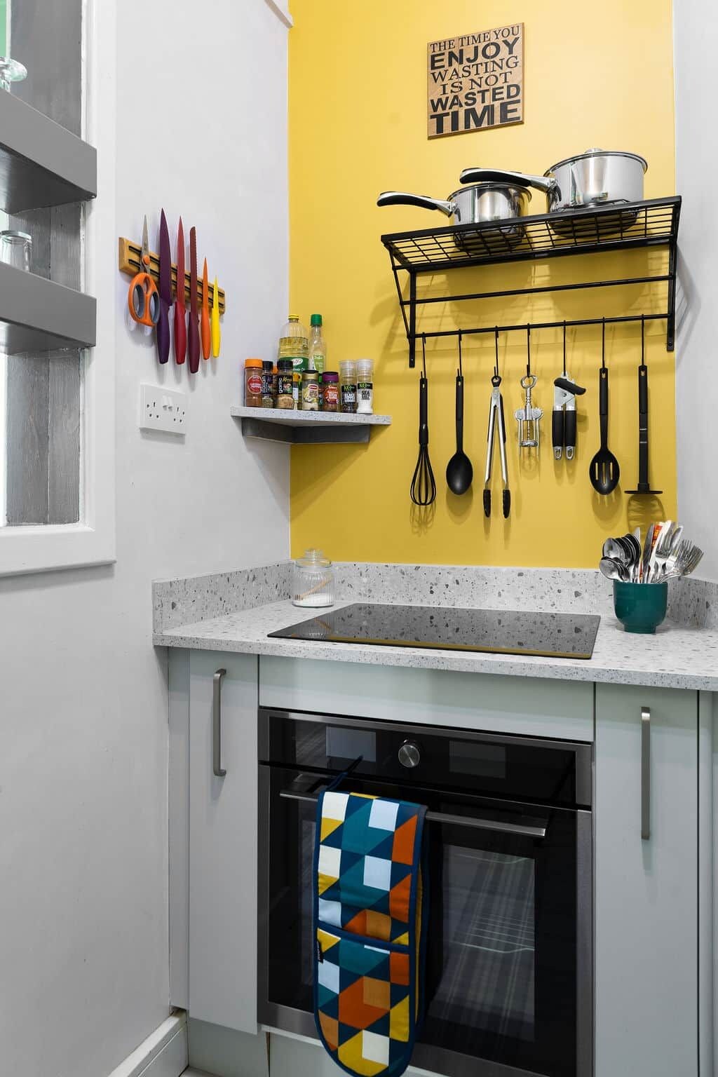 A kitchen with a yellow accent wall, a hanging pot rack, and various utensils.