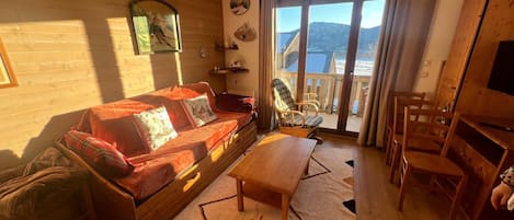 Una sala de estar acogedora con un sofá, una mesa de centro de madera y vistas a un paisaje nevado a través de una puerta corrediza de vidrio.
