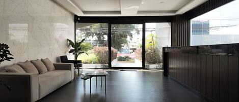 A modern living room with a sofa, a coffee table, and a large window offering a view of the outdoors.