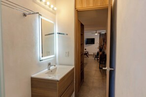 A bathroom with a vanity, mirror, and a ceiling fan. - San Luisito departamentos (Puerto Vallarta)