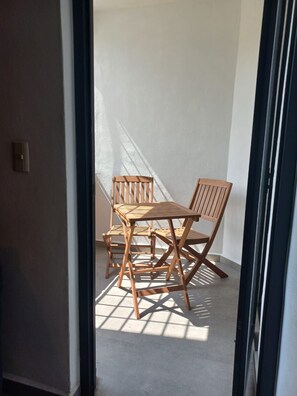 A room with a wooden table and chairs, a door, and a light-colored wall. - Departamento San Luisito (Puerto Vallarta)