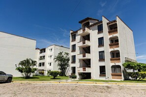 A multi-story residential building with balconies and a paved street in front. - Departamento San Luisito (Puerto Vallarta)