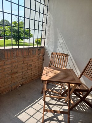 A corner room with a brick wall, a window with metal bars, and a wooden table and chairs. - Departamento San Luisito (Puerto Vallarta)