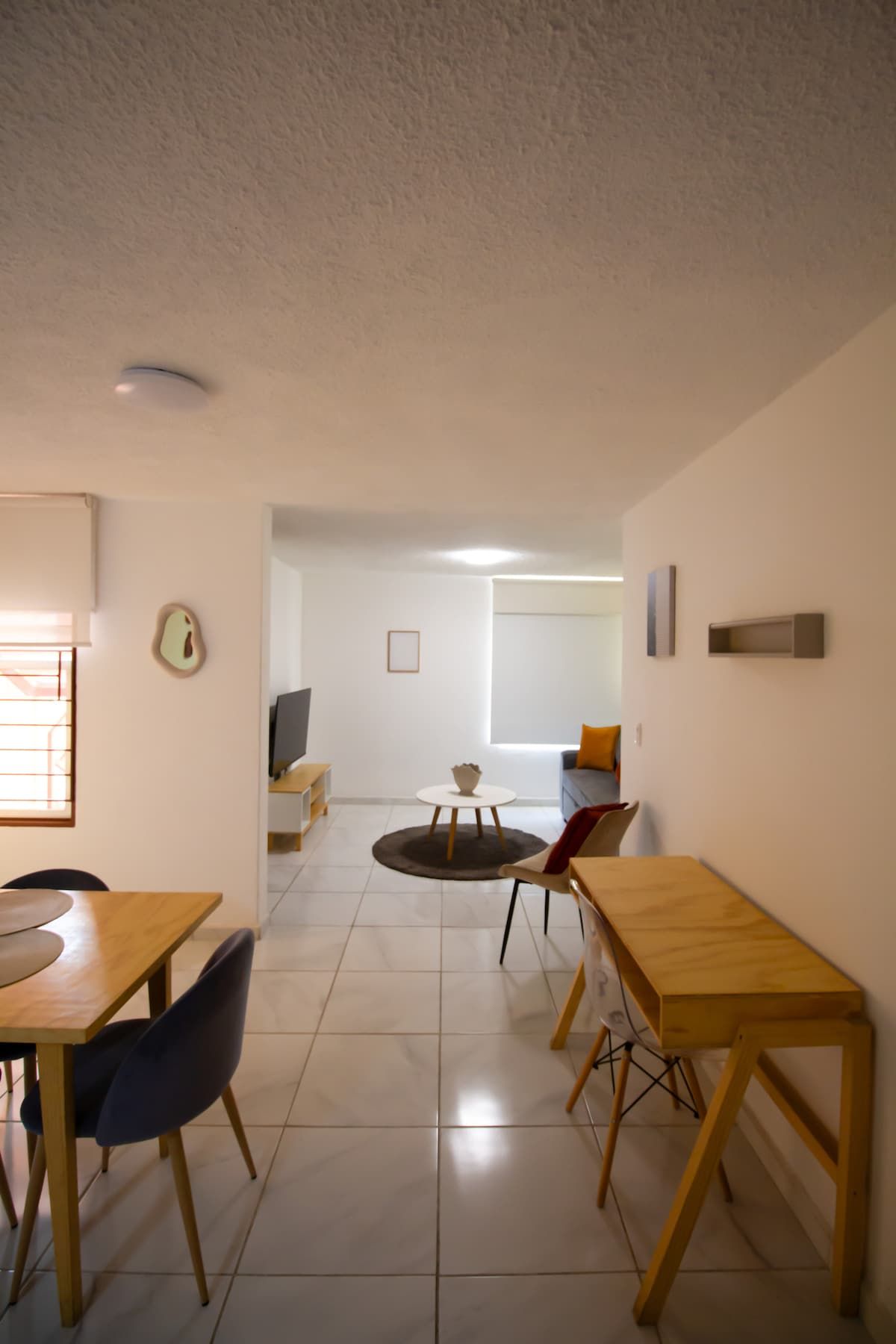 A modern living room with a dining area, a TV, and a sofa.