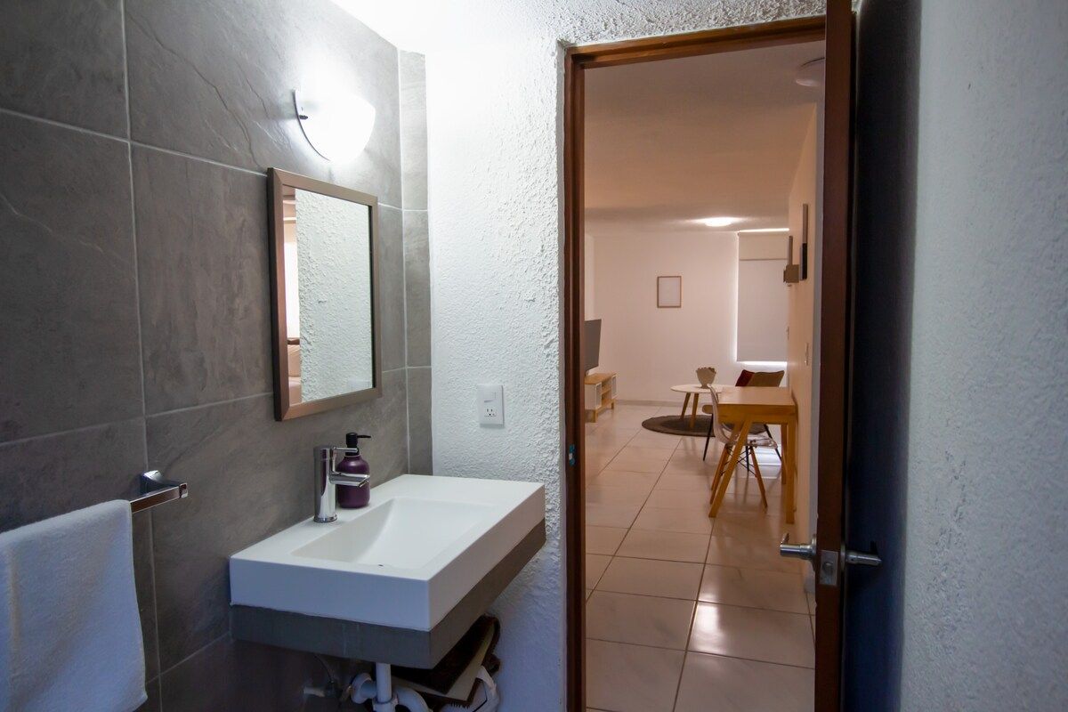 A bathroom with a white sink, a mirror, and a towel rack.
