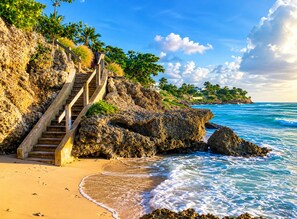 A coastal walkway leading to a beach with ocean views, a staircase, and palm trees. - Atlantic Shores - 1 Bedroom Apartment (Christ Church)