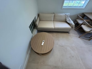 A room with a sofa, a round table, and a window. - Atlantic Shores - 1 Bedroom Apartment (Christ Church)