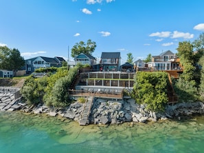 A waterfront property with multiple houses, a dock, and a clear view of the water. - Cottage-Waterfront, Hot Tub, Private Beach, Kayaking, Fireplace, Games & Sunset (Clarington)