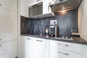 Eine moderne Küche mit integriertem Mikrowellenherd, Kaffeemaschine und Wasserkocher.