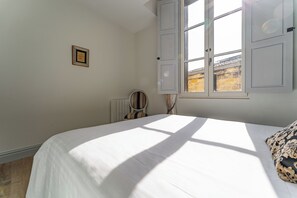 Ein Schlafzimmer mit einem Bett, einem Fenster und einer Heizung.
