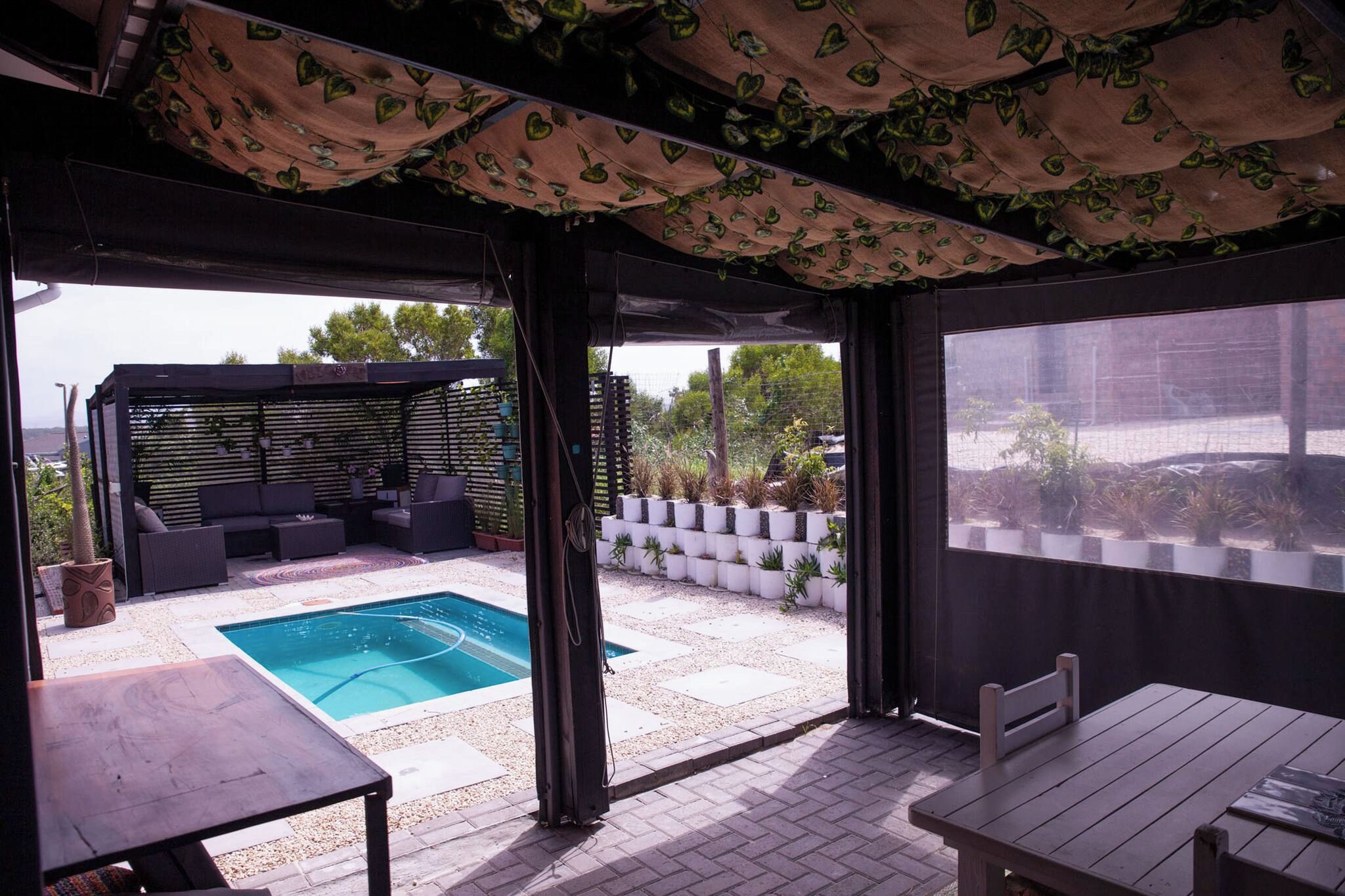 Un patio al aire libre con piscina, zona de estar y una sección cubierta con toldo estampado.
