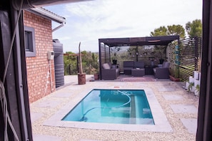 A backyard with a swimming pool, outdoor seating, and a brick wall. - Langa Elihle on Paradise Beach (Paradise Beach)