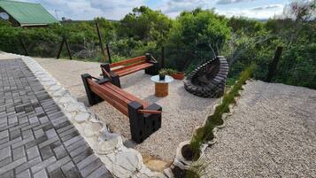 Un espacio al aire libre con asientos, una banca, una mesa redonda y un original hogar de piedra.