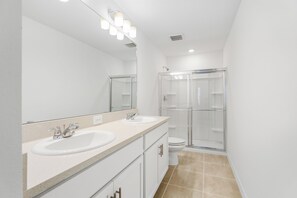 Un bagno moderno con un doppio lavabo, un ampio specchio e una doccia vetrata.